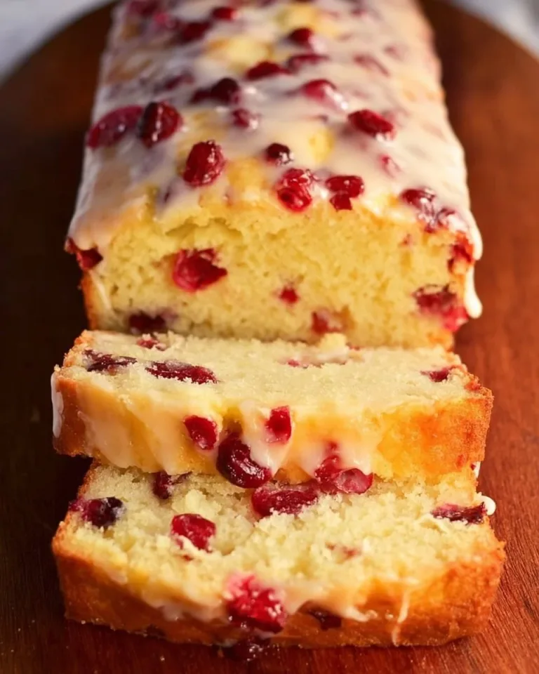 Homemade Orange Cranberry Bread with a citrusy glaze on a wooden surface