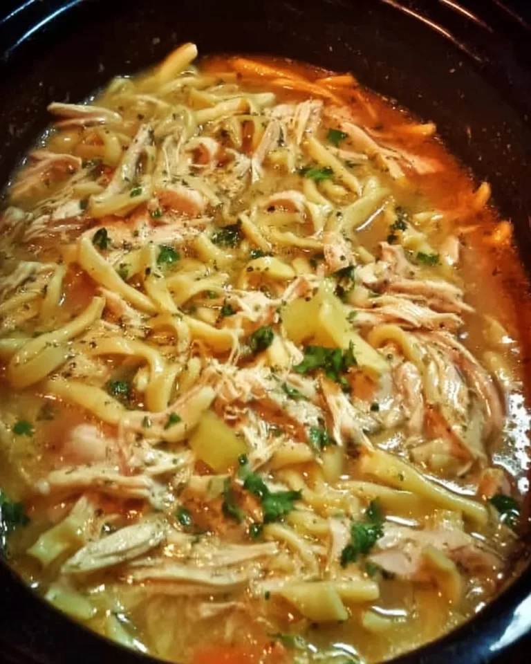 Bowl of chicken noodles cooked in a crock pot, garnished with herbs