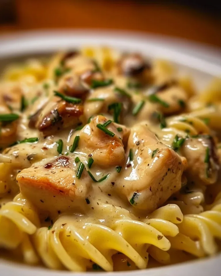 Creamy chicken rotini dish served in a bowl with fresh herbs