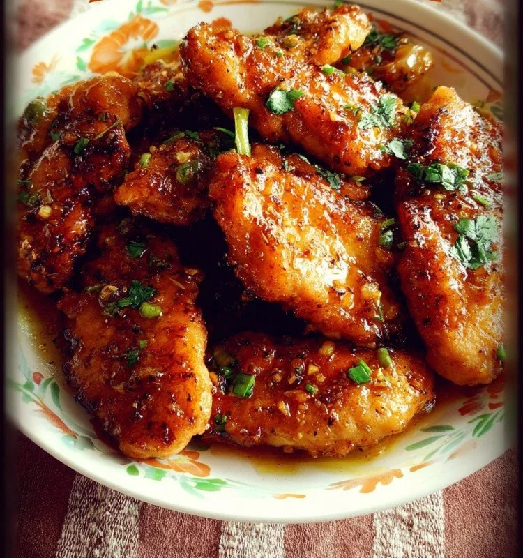 Plate of honey garlic chicken tenders glazed with sauce.
