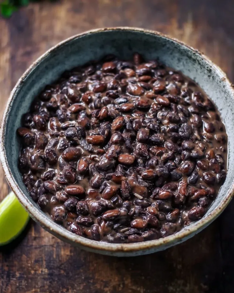 Bowl of creamy refried black beans served with tortilla chips and salsa